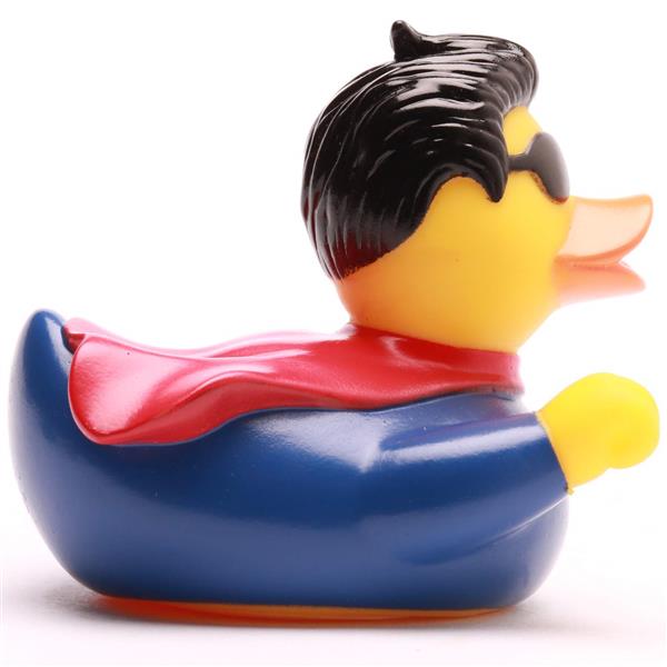 Un canard en caoutchouc déguisé en super-héros, portant une cape rouge, une tenue bleue, des cheveux noirs et des lunettes de soleil noires, tourné vers la droite.