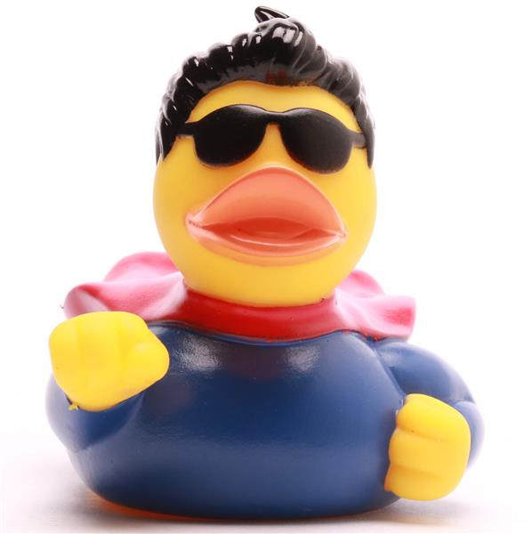 Un canard en caoutchouc déguisé en super-héros, avec une cape rouge, une tenue bleue, des cheveux noirs et des lunettes de soleil noires, levant un poing jaune.