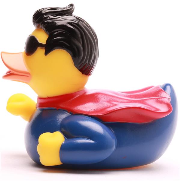 Un canard en caoutchouc déguisé en super-héros, portant une cape rouge, un costume bleu et des lunettes de soleil noires, avec des cheveux noirs coiffés.
