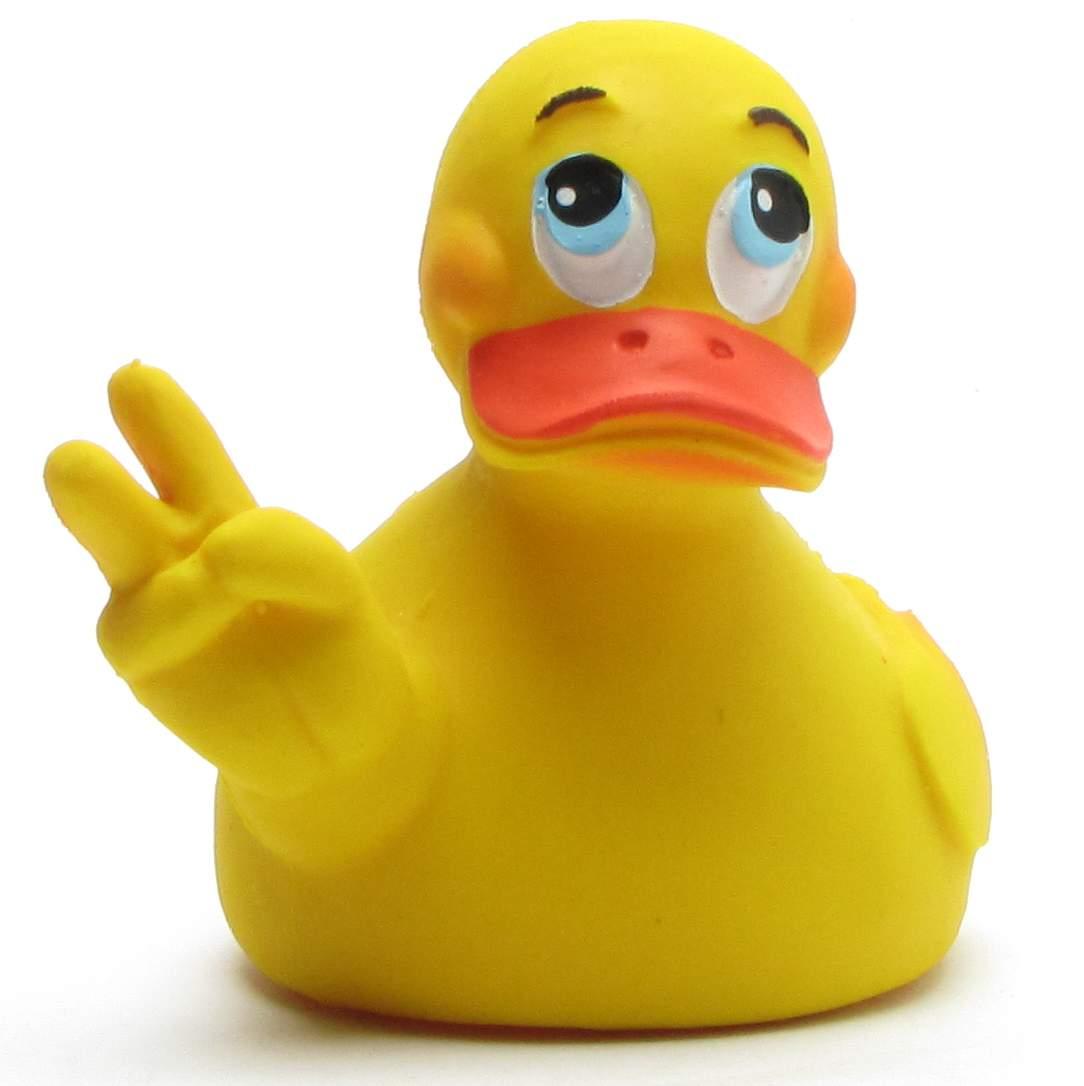 Un canard en caoutchouc jaune, aux grands yeux bleus et au bec orange, lève son aile gauche pour former le signe de la paix.