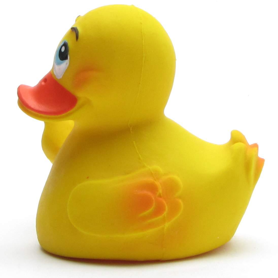 Un canard en caoutchouc jaune, au bec et aux ailes orange, souriant et tourné vers la gauche, sur fond blanc.