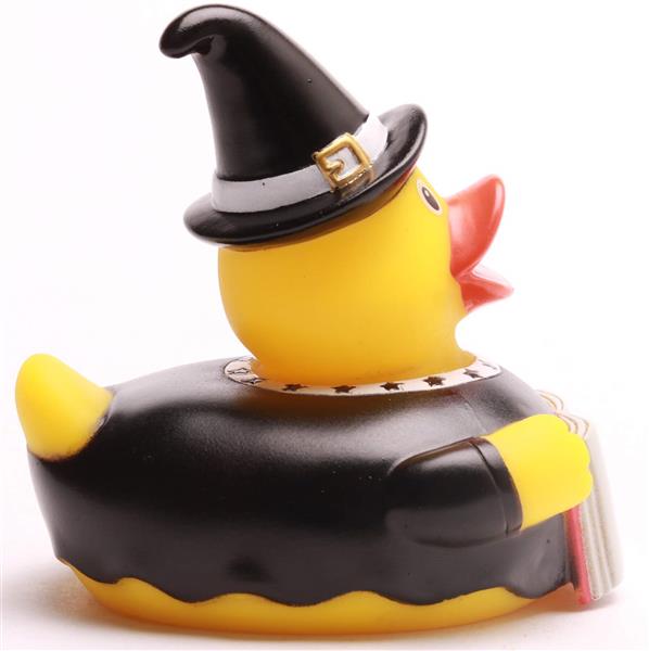 Un canard en caoutchouc jaune déguisé en sorcière, coiffé d'un chapeau noir et d'une cape, tenant un petit livre.