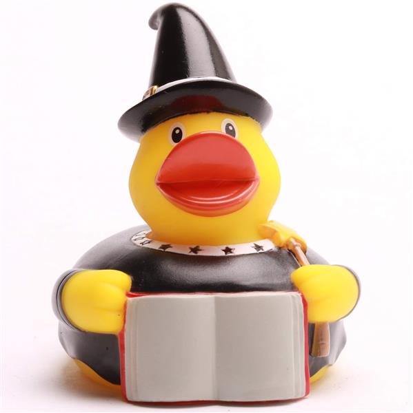 Un canard en caoutchouc déguisé en sorcière, coiffé d'un chapeau noir et vêtu d'une robe noire, tenant un livre ouvert.
