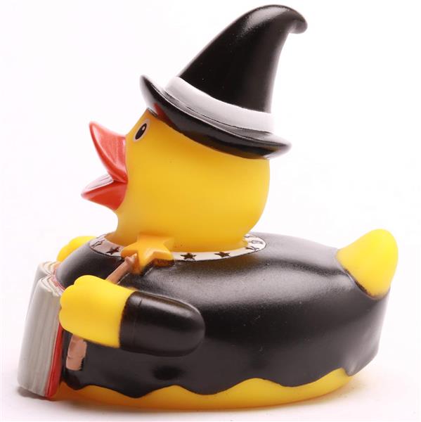 Un canard en caoutchouc jaune déguisé en sorcière, coiffé d'un chapeau noir et d'une cape, tenant une baguette magique et un livre.
