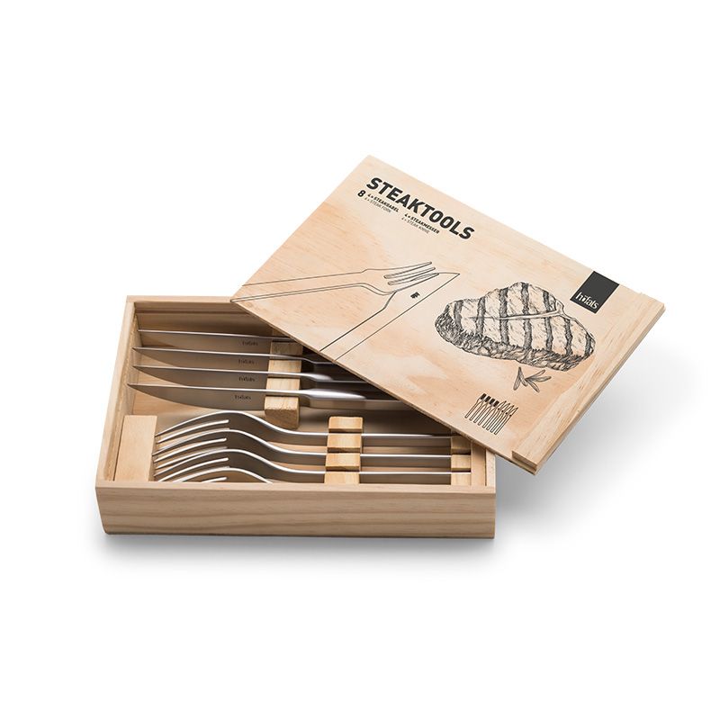 Une boîte en bois portant l'inscription « Coffret couverts à steak en acier inoxydable forgé » contient quatre couteaux à steak et quatre fourchettes, soigneusement rangés à l'intérieur, avec une illustration représentant un steak et des couverts sur le couvercle.