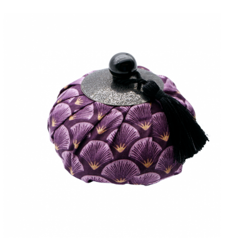 Aumônière parfumée « Ananas vert » – Parfum patchouli : une boîte ronde recouverte de tissu, ornée d'un motif en éventail violet et doré, agrémentée d'un bouton noir et d'un pompon.