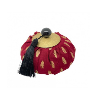 Aumônière parfumée « Ananas vert » – Parfum patchouli : une aumônière ronde en tissu rouge ornée de motifs dorés, dotée d'un rabat doré, d'une perle noire et d'un pompon noir.